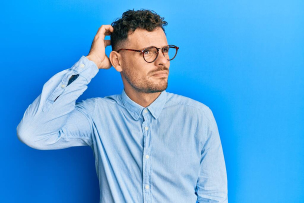 Young hispanic man wearing casual clothes and glasses confuse and wondering about question. uncertain with doubt, thinking with hand on head. pensive concept.  - Foto, Bild