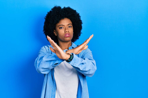 Jonge Afro-Amerikaanse vrouw draagt casual kleding afwijzing uitdrukking kruisen armen en palmen doen negatief teken, boos gezicht  - Foto, afbeelding