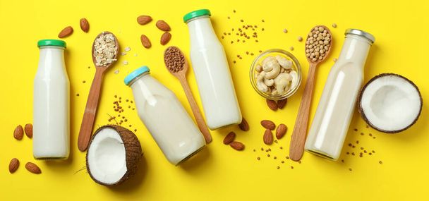 Concept of vegan milk on yellow background, top view - Фото, изображение