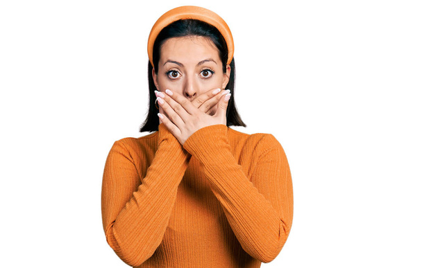 Jong Latijns-Amerikaans meisje draagt casual wit t-shirt geschokt bedekken mond met handen voor fout. geheim concept.  - Foto, afbeelding