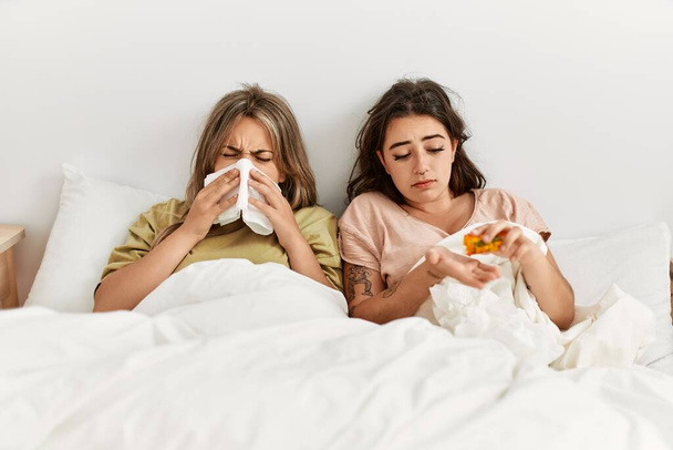 Jeune couple malade utilisant une serviette et mangeant des pilules allongées sur le lit à la maison. - Photo, image