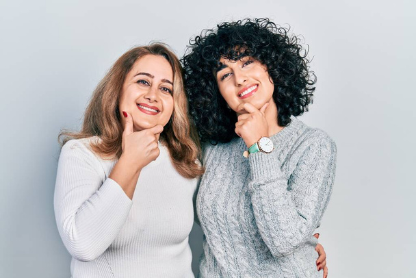 Middle east mother and daughter wearing casual clothes looking confident at the camera smiling with crossed arms and hand raised on chin. thinking positive.  - Photo, Image
