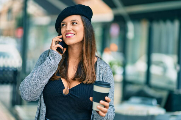 Jeune femme latine parlant sur le smartphone boire du café à la ville. - Photo, image
