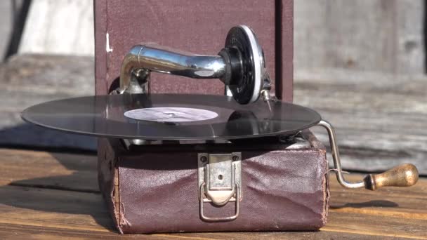 Oude kleine bruine grammofoon fonograaf buiten. vinyl plaat draait. close-up - Video