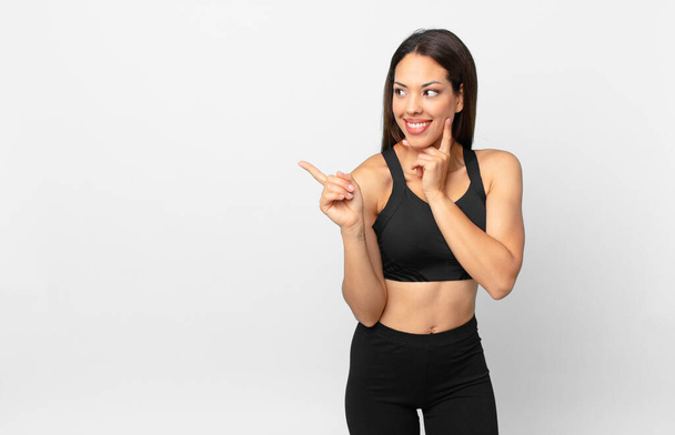 young hispanic woman smiling happily and daydreaming or doubting. fitness concept - Photo, Image