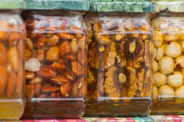 Nootsets. Noten in blik met honing in glazen potten. Oogst van noten. Delicacy en gezond voedsel. Zelfgemaakte conservering in de herfst. - Foto, afbeelding