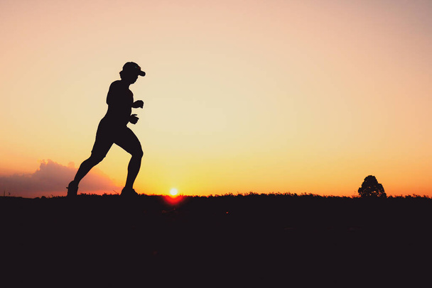 Silhouette of a man practicing for a run in the evening. Training and running concepts - Photo, Image