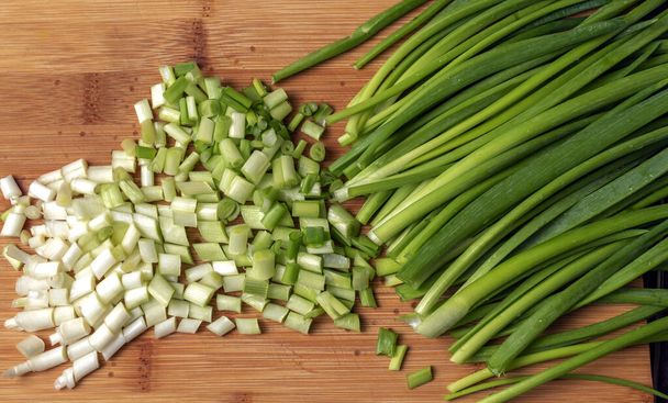 Top view of chopped green spring onions on wooden board. - Photo, Image