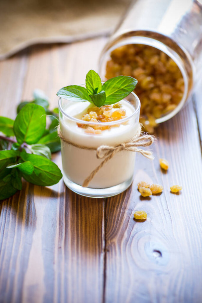 sweet homemade yogurt with raisins in a glass on a wooden table - Foto, immagini