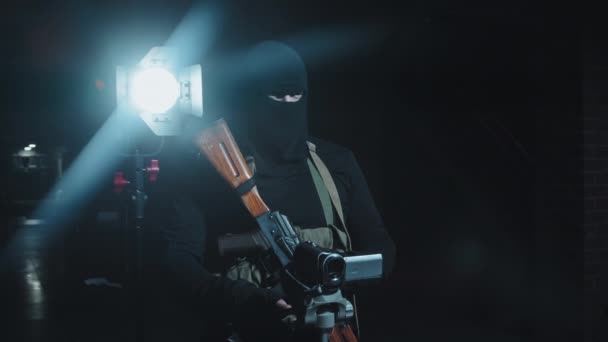 Langzaam volgen shot van onherkenbare gewapende terrorist met wapen filmen gijzelaar off camera - Video
