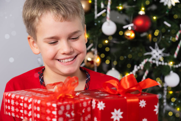 Happy Smiling Child with Christmas gift Boxes Near Christmas Tree. Christmas and New Year Holidays Concept - Zdjęcie, obraz
