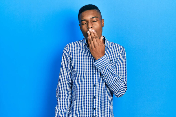 Junge afrikanisch-amerikanische Mann in lässiger Kleidung gelangweilt gähnend müde Mund mit der Hand bedecken. Ruhelos und schläfrig.  - Foto, Bild