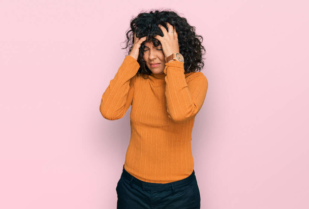 Young hispanic woman wearing casual clothes suffering from headache desperate and stressed because pain and migraine. hands on head.  - Photo, Image