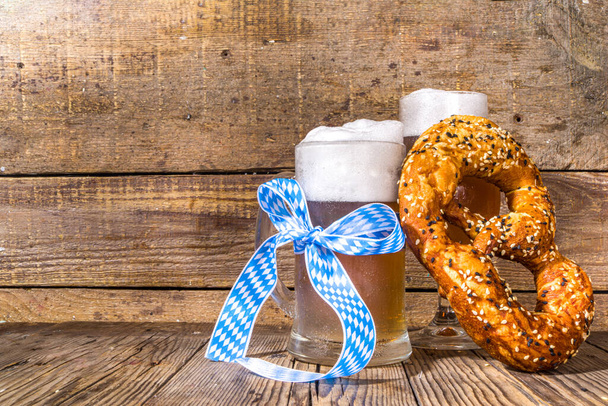 Oktoberfest various beer glasses and mugs with pretzel, wheat and hops. Bar and pub menu, invitation card background on wooden background copy space - Zdjęcie, obraz