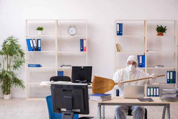 Egy öreg férfi takarítja az irodát seprűvel - Fotó, kép