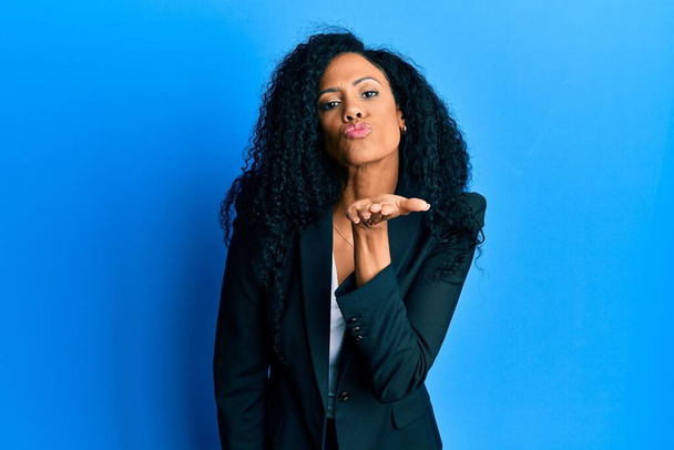 Middle age african american woman wearing business clothes looking at the camera blowing a kiss with hand on air being lovely and sexy. love expression.  - Foto, imagen