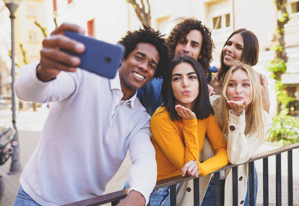 Wieloetniczna grupa przyjaciół robi sobie selfie na ulicy smartfonem. - Zdjęcie, obraz