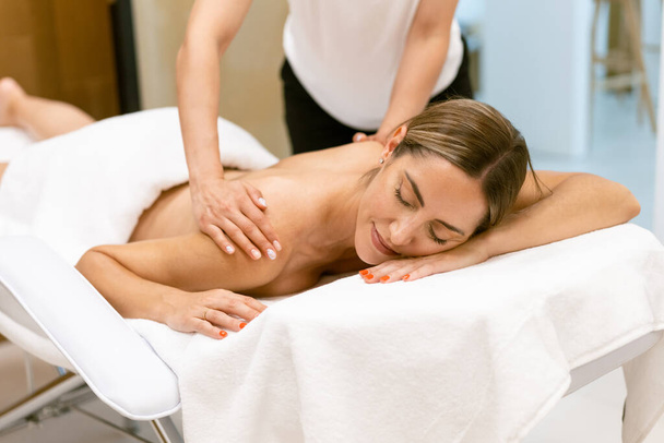 Middelbare leeftijd vrouw met een rug massage in een schoonheidssalon. - Foto, afbeelding