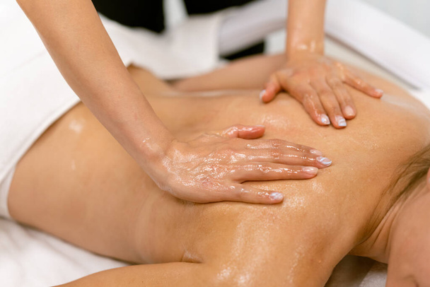 Vrouw ontvangt rugmassage met massage kaarsenolie. - Foto, afbeelding