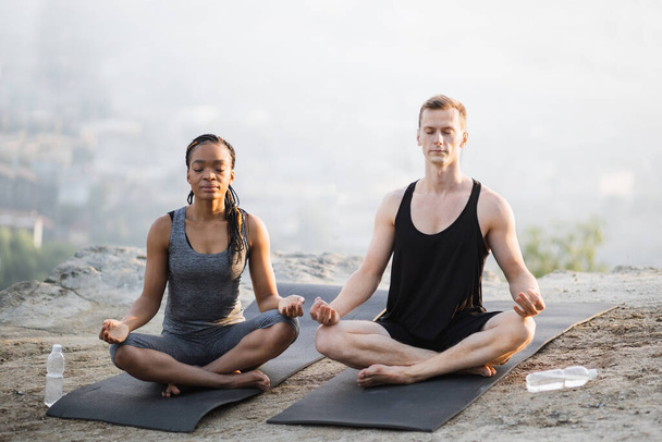 Multicultural couple meditation on yoga mat outdoors - Foto, Imagem