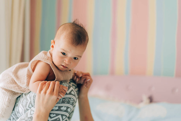 Genç bekar bir anne karantina sırasında bebeğiyle yatakta oynar. Çocuk evlat edinme ve tüp bebek. . - Fotoğraf, Görsel