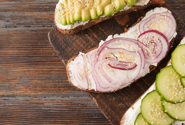 sandwiches with , cucumber , soft cheese and avocado slices, red onion on a wooden , top view - 写真・画像