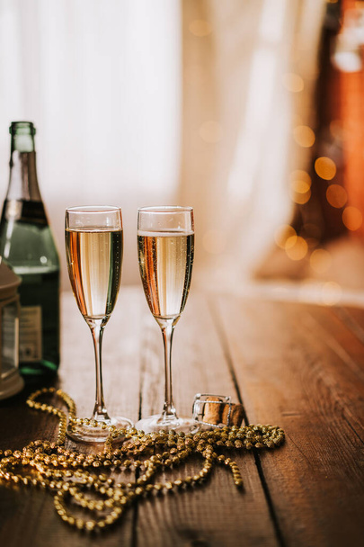 Dvě sklenice se šampaňským a lahví na dřevěném stole. Svislá fotografie - Fotografie, Obrázek
