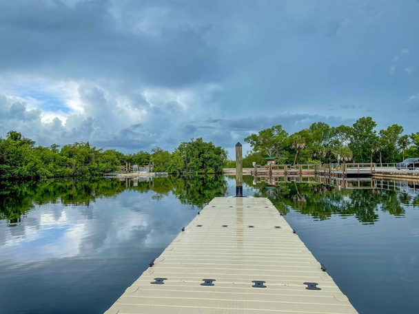 Stormwolken weerkaatsen in de kalme wateren van Collier-Seminole State Park 's jachthaven in de buurt van het drijvende dok. - Foto, afbeelding