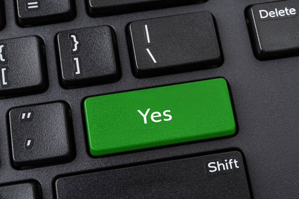 Keyboard with Yes button. Green key with Yes words on a black desktop computer keyboard. Confirm, verify, agree the terms and and accept the rules concepts. Keypad enter button with message. Top view. - Foto, Imagem