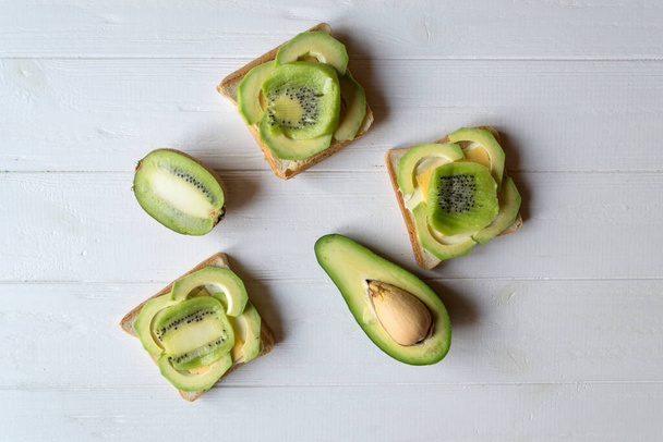 The sandwiches with avocado and kiwi on a white wooden background. - Foto, immagini