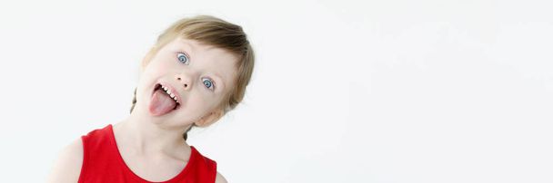 Bambina in abito rosso mostrando la lingua - Foto, immagini