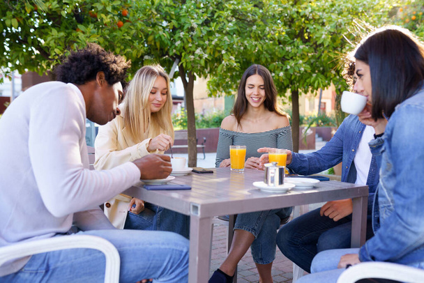 Grupo multiétnico de amigos tomando una copa juntos en un bar al aire libre. - Foto, Imagen