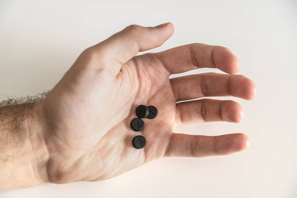Pilules dans la main. Des pilules noires. Contexte des soins de santé. Papier peint médecine - Photo, image