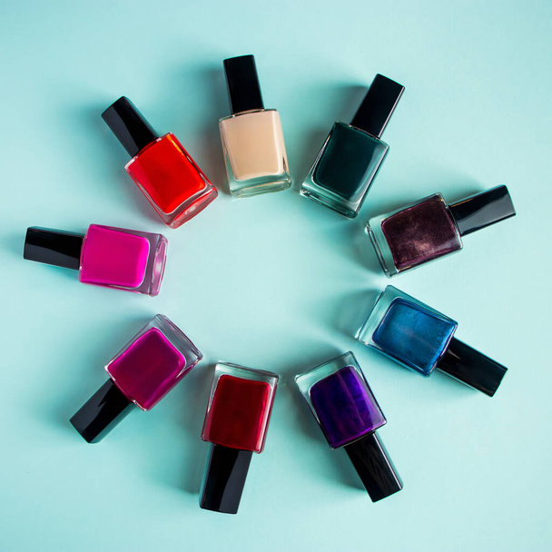 Group of bright colored nail polishes on a blue background. Set of decorative cosmetics for body care. - Photo, Image