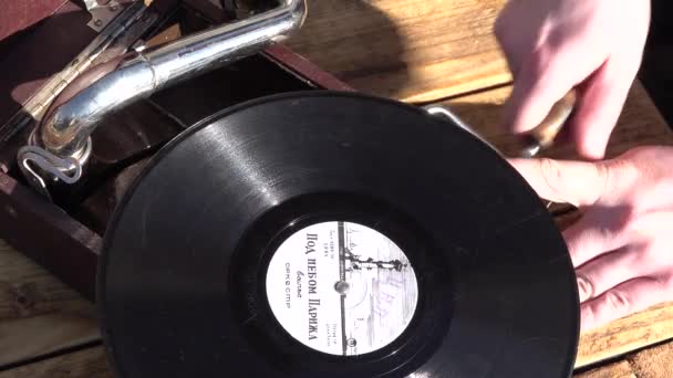 La mano del hombre enciende el mecanismo de gramófono para reproducir música de vinilo. de cerca  - Metraje, vídeo