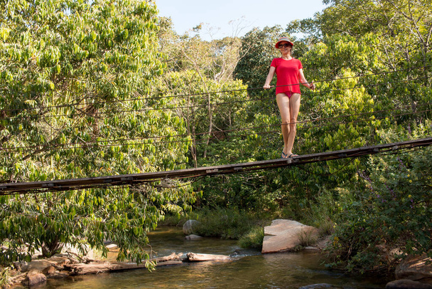 Леді у червоному положенні на малому озері перемикає міст через Ро - дас - Альмас, що на території Бразилії. - Фото, зображення