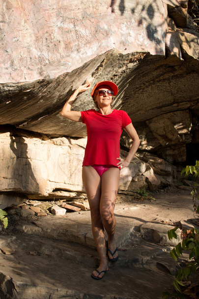 Maturo signora in rosso in posa da una grande roccia all'interno del Brasile - Foto, immagini