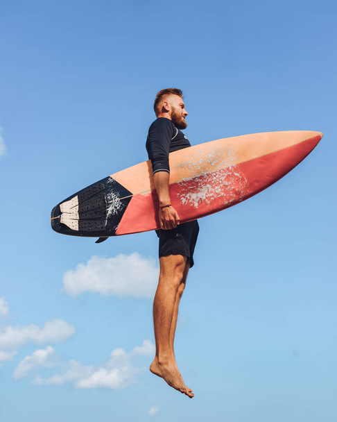 A European surfer with a surf board in the sky. Jump into the sky - Фото, изображение