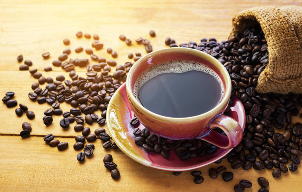 Gorące kawy espresso lub americano i ziarna kawy na starszym drewnianym stole w godzinach porannych. Przerwa na kawę. - Zdjęcie, obraz