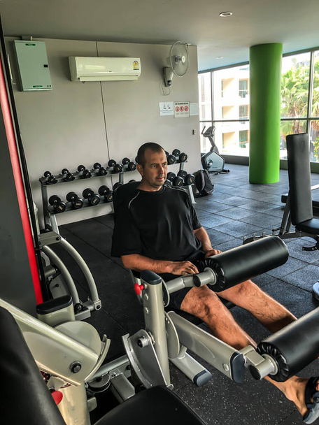Man is engaged in sports, makes exercises on simulators in the gym - Foto, Imagen