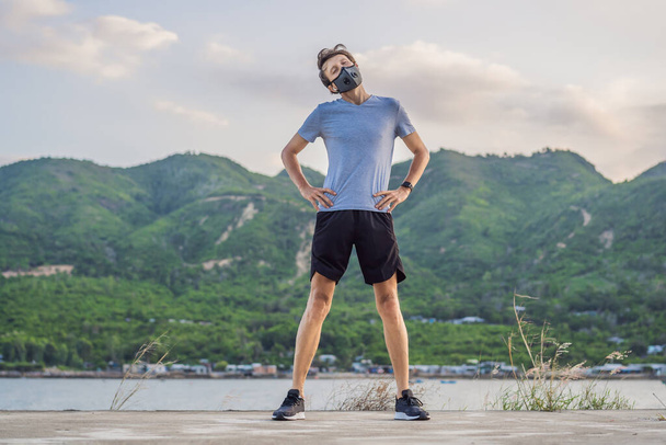 Runner wearing medical mask, Coronavirus pandemic Covid-19. Sport, Active life in quarantine surgical sterilizing face mask protection. Outdoor run on athletics track in Corona Outbreak - Photo, Image