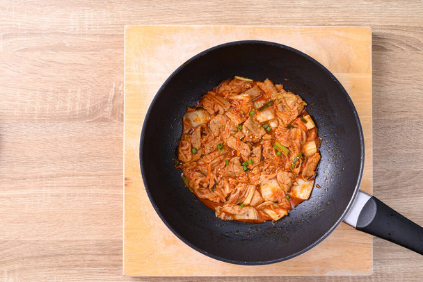 Gebratenes Schweinefleisch mit Kimchi-Kohl in der Pfanne, hausgemachtes koreanisches Essen, Tischansicht - Foto, Bild