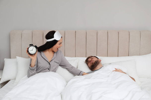 Emotional woman waking up man in bedroom. Being late concept - Fotó, kép
