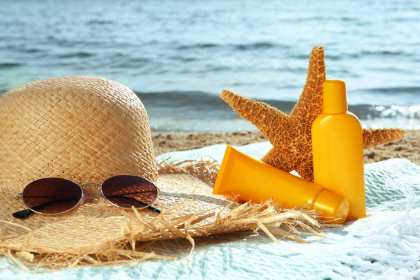 Sun protection products and beach accessories on blanket near sea - Valokuva, kuva