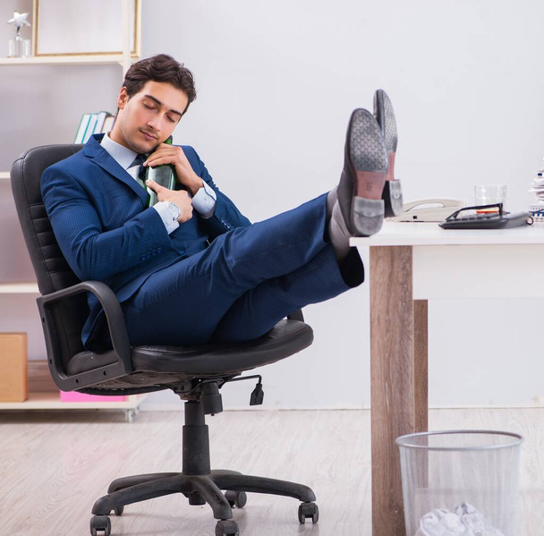 Young businessman employee drinking in the office at desk - Photo, Image