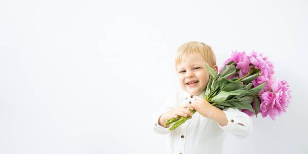 banner. little blonde boy with big bouquet of pink peonies on white background. Love and romantic concept - Photo, Image