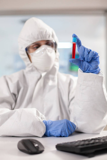 Close up of blood sample while medical researcher looking at it - Photo, image