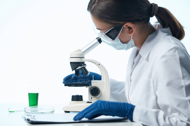 mujer científica mirando a través de un microscopio investigación biología diagnóstico - Foto, Imagen