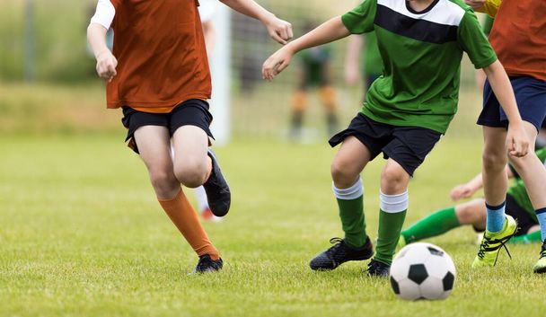 Grupa młodzieżowych piłkarzy biegających za piłką. Młodzi chłopcy na meczu. Dzieci w szkole w konkursie sportowym - Zdjęcie, obraz