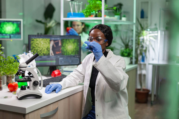 Primer plano de la mujer científica africana mirando la muestra de prueba de la hoja - Foto, Imagen